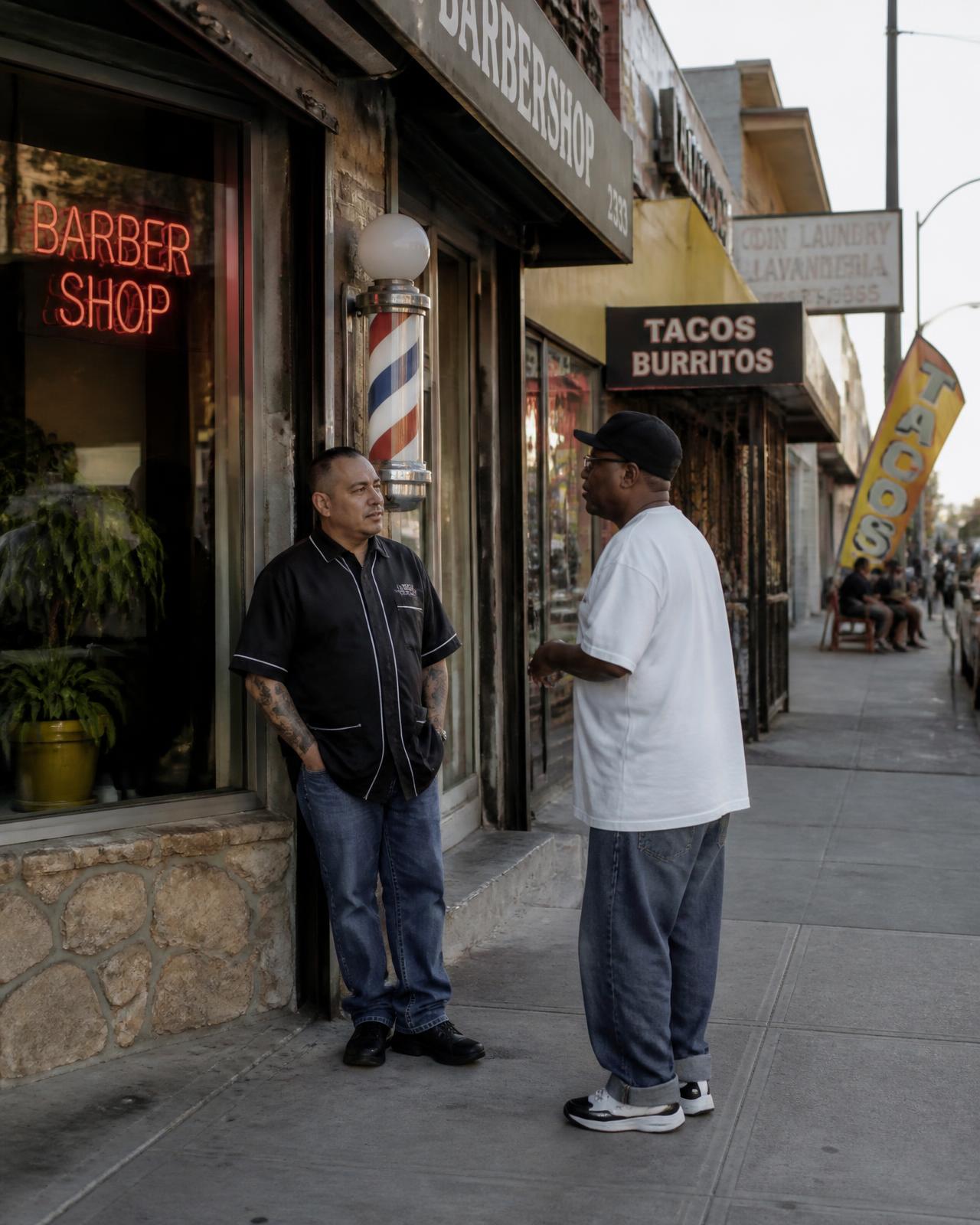 Two men talking outside a neighborhood barbershop