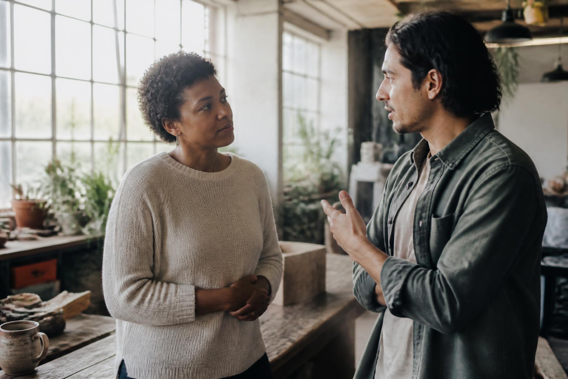 A woman and a colleague talking and listening to each other in a daylit workspace